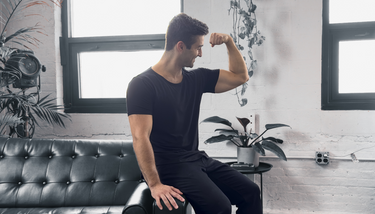 man flexing wearing the onyx black short sleeve drop tee