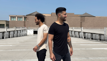 2 men standing together wearing the short sleeve drop tee in onyx black and sand beige